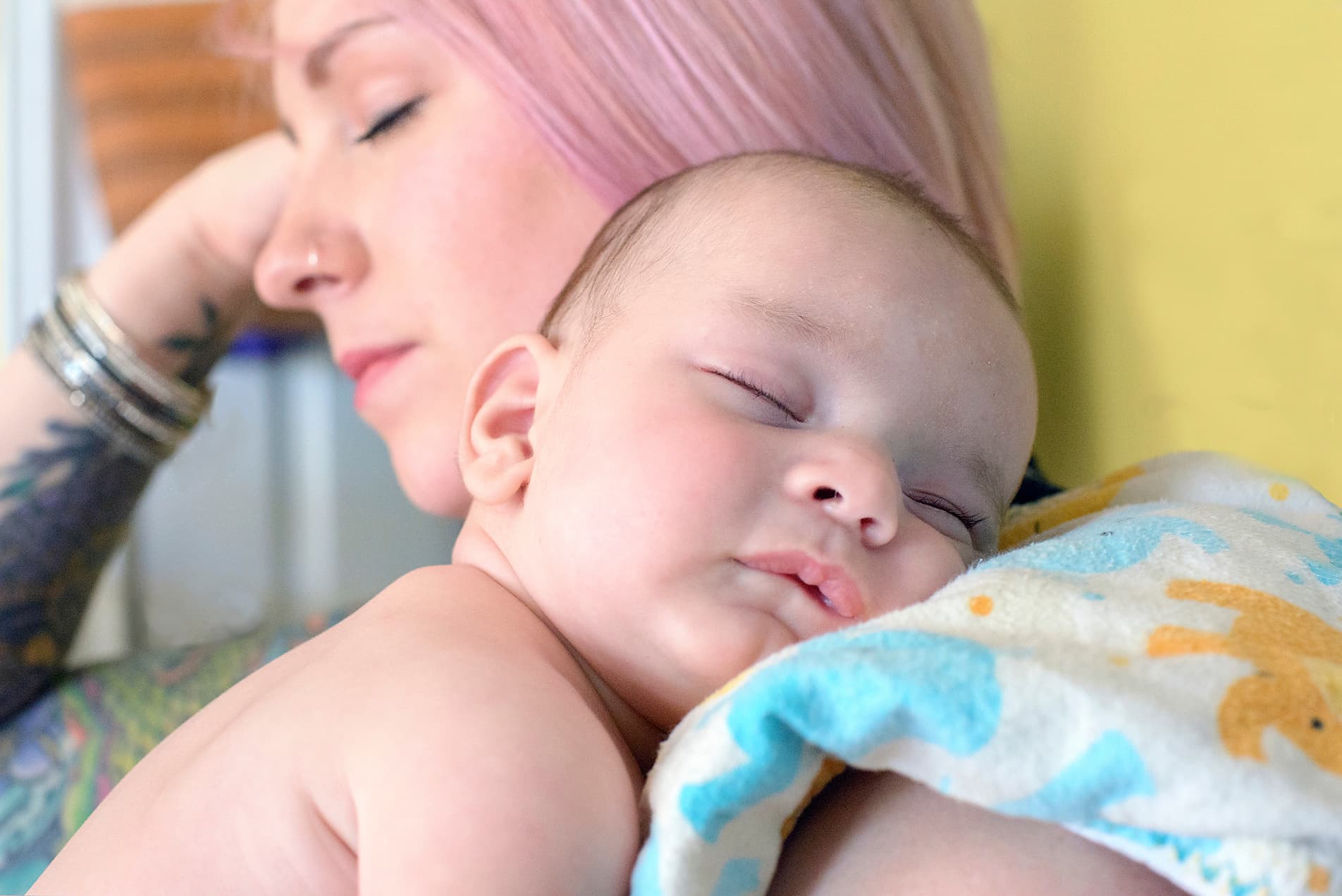 Mother peacefully holding sleeping baby with Cool Cuddle sling